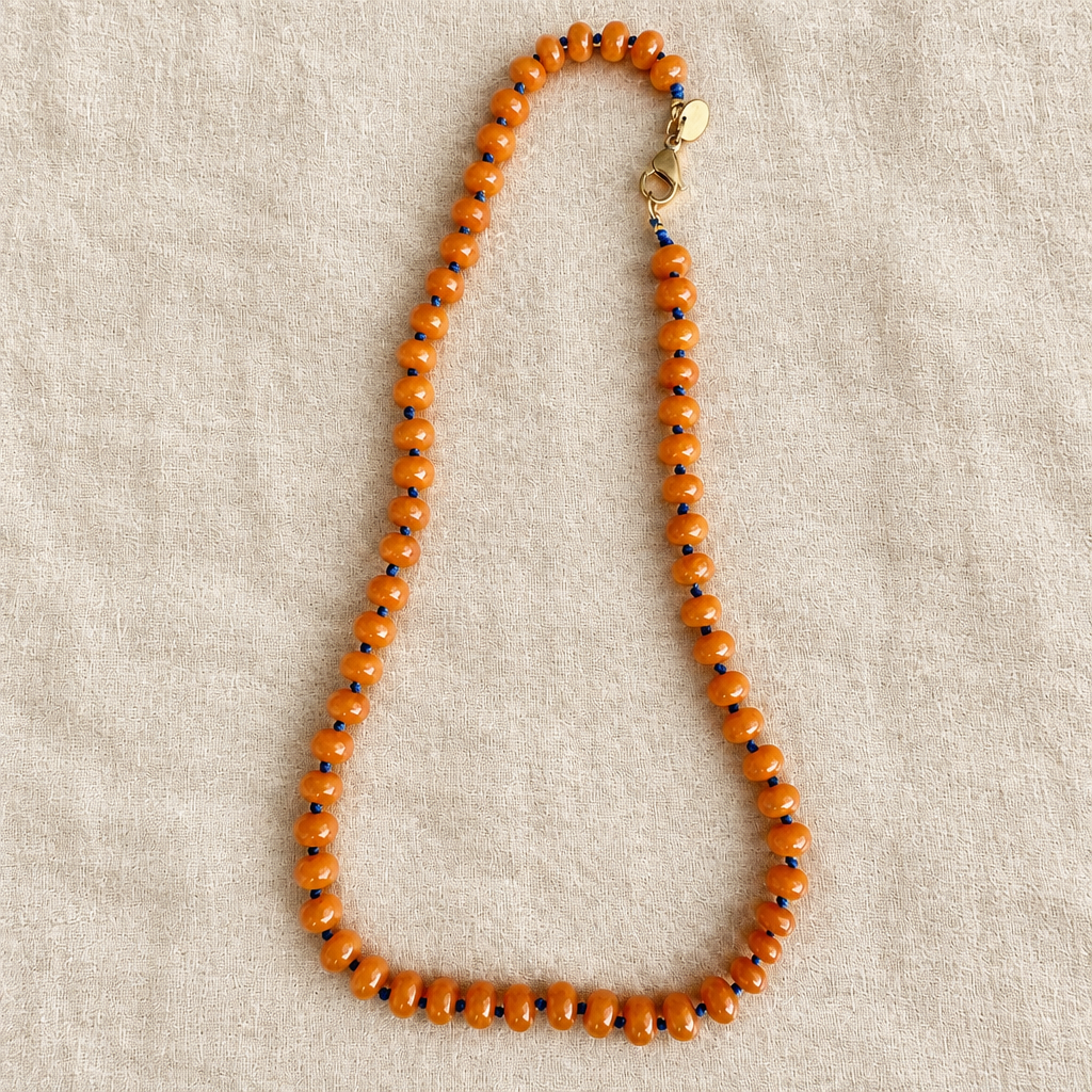 Collar naranja sobre tela rústica crema, foto 2