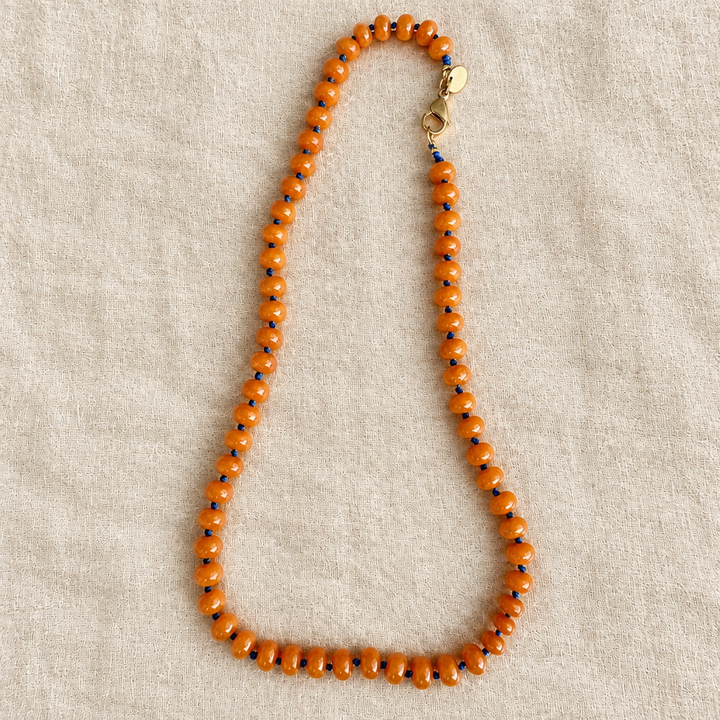Collar naranja sobre tela rústica crema, foto 2
