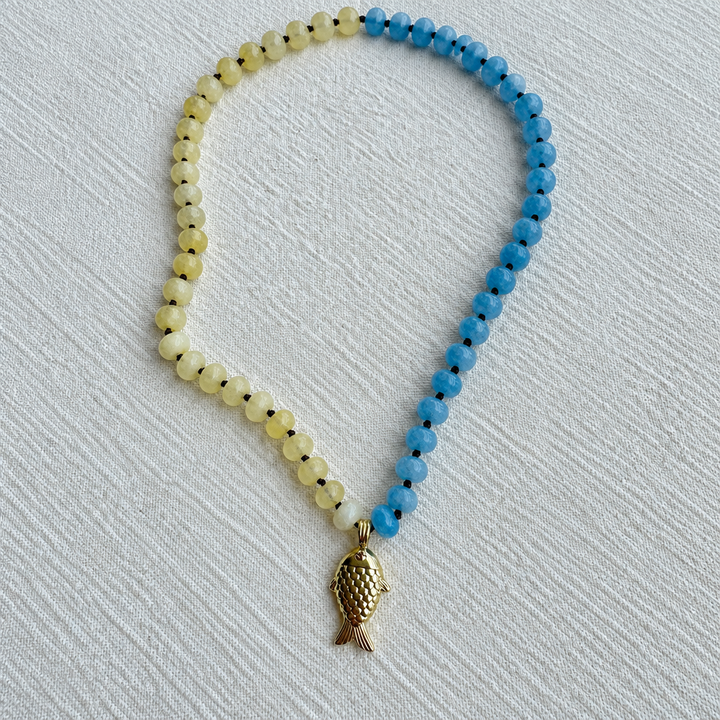 Collar pez amarillo y azul sobre tela, detalle